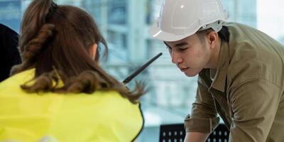 trabajo en equipo en construcción sitio, civil ingeniero o profesional capataz en la seguridad casco difícil sombrero utilizando Plano en mientras en pie a industrial fábrica, trabajo en equipo concepto foto