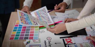 UX Developer and UI Designer Brainstorming Session with Color Palettes and Wireframes on Desk photo