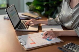 Businesswoman using laptop computer and working at office with calculator document on desk, doing planning analyzing the financial report, business plan investment, finance analysis concept photo