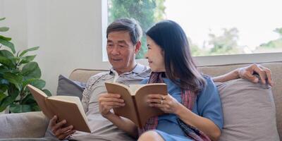 Elderly Couple Enjoying Quality Time Reading Books Together on a Cozy Sofa in a Bright Living Room photo