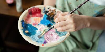 Artist Painting in Workshop with Palette and Brush, Creating Colorful Artwork in Studio, Close Up of Hand and Paints, Creative Process, Artistic Expression, Professional Art Studio Environment photo