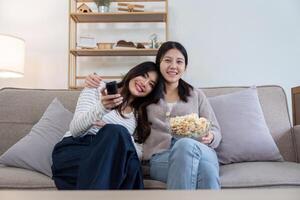 Cozy Lesbian Couple Enjoying TV Time at Home on a Comfortable Sofa with Snacks and Smiles photo