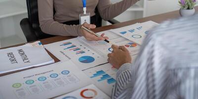 Two Business Professional Discussing Planning and Analysis with Charts and Graphs in a Modern Office Setting photo