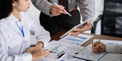 Business Team Discussing Analysis and Planning in a Meeting with Charts and Graphs on a Tablet and Documents photo