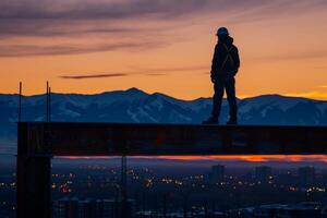 A construction worker standing silhouetted against the skyline photo