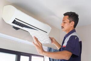Man fixing air conditioning system, Technician cleaning air conditioner indoors, Repairman washing dirty compartments air conditioner photo