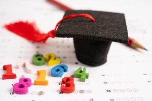Graduation gap hat and pencil on answer sheet paper, Education study testing learning teach concept. photo