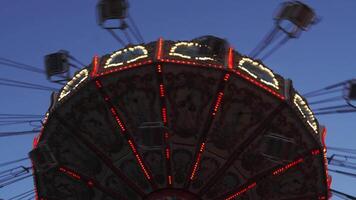 Illuminated Swing Ride Against a Twilight Sky with Motion Blur of Swings at an Amusement Park video