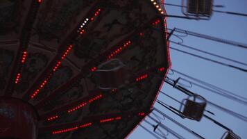 Low Angle View of a Swing Carousel Ride at Night with Bright Lights and Moving Seats Against a Twilight Sky video