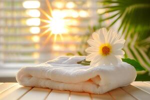 White towel with flower on wooden table in spa salon, closeup photo