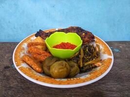 a plate of grilled fish, complete with chili sauce and fresh vegetables photo