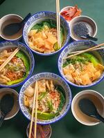 Noodle soup with wonton dumplings and vegetables. separate sauce. Top view photo