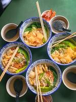 Noodle soup with wonton dumplings and vegetables. separate sauce. Top view photo