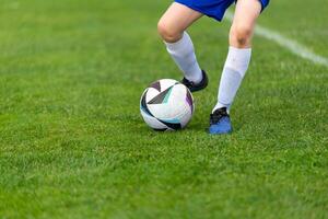 Young soccer player's kick ball. Ball and legs in sharp focus on a lush green field close-up photo