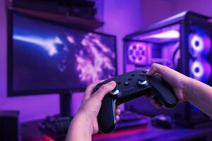 Immersive gaming setup featuring a gamer playing on a gaming PC with a gamepad, set in a gamer room with a gaming desk and LED lights photo