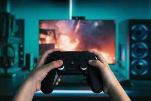 Dynamic image of hands holding a gamepad in front of a modern gaming computer, with vibrant LED lights, playing an action-packed game photo