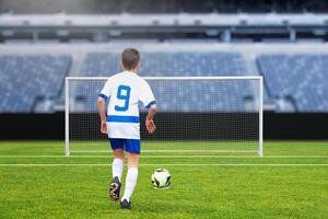 Young football player taking a penalty shot on an empty goal at a modern stadium, capturing the excitement of the game photo