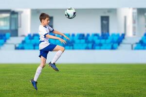 Young soccer player leaps into the air, using his head to direct the ball in a dynamic and intense soccer match scene photo