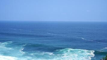 view of the beach from the top of the cliff, small waves and white foam photo