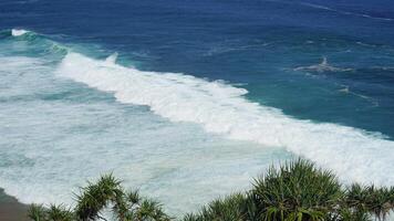 view of the beach from the top of the cliff, small waves and white foam photo