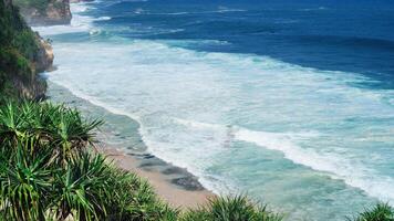 view of the beach from the top of the cliff, small waves and white foam photo