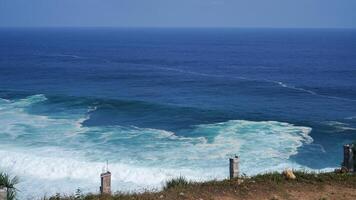 view of the beach from the top of the cliff, small waves and white foam photo