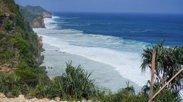 view of the beach from the top of the cliff, small waves and white foam photo