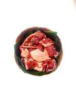 closeup of sacrificial goat meat in a bamboo container isolated on white background photo