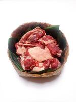 closeup of sacrificial goat meat in a bamboo container isolated on white background photo