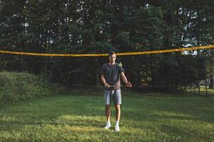 Black-haired badminton player practices his strokes on the grass court. Individual technique training. Amateur concept of the sport. The joy of the game photo