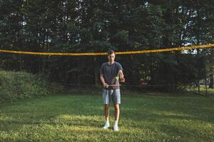 Black-haired badminton player practices his strokes on the grass court. Individual technique training. Amateur concept of the sport. The joy of the game photo