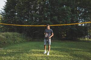 Addicted to the mobile phone even when playing badminton. A black-haired man holding a phone and playing sport. Modern combination of sport and technology. Problem of teenagers today photo