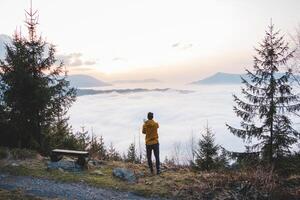 Adventurer takes photos on his mobile phone to capture the sunset and the clouds below. Capturing memories with technology. Beskydy mountains, Czech Republic