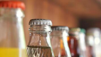 Vintage beverage bottles with colorful caps on bar shelf create a nostalgic retro drinks display video