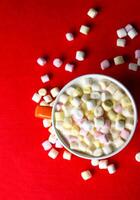 Cocoa drink with colorful small marshmallows on red background photo