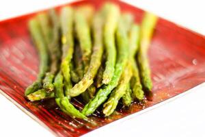 Green grilled asparagus on a red plate photo