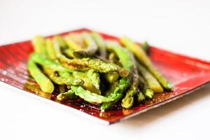 Green grilled asparagus on a red plate photo