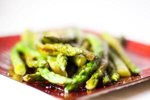 Green grilled asparagus on a red plate photo