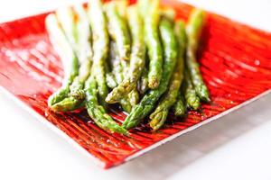Green grilled asparagus on a red plate photo