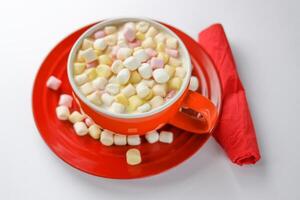 Cocoa drink with colorful small marshmallows on red background photo