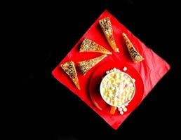 Cocoa drink with colorful small marshmallows on red background photo