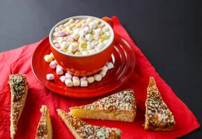 Cocoa drink with colorful small marshmallows on red background photo