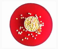Cocoa drink with colorful small marshmallows on red background photo