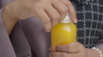 Carefully opening a yellow beverage bottle with hands, focusing on precision and relaxation video