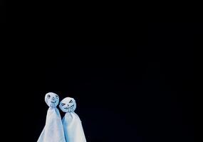 Decoration for Halloween. Two ghost figures on black background. Handmade decor for party. photo