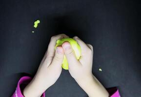 Girl playing with yellow slime in her hands. photo