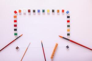 Watercolor paints, brushes and paper on white background. Flat lay, top view photo