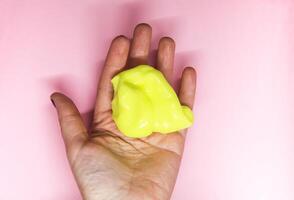 Girl playing with yellow slime in her hands. photo