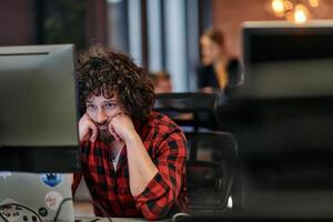 Disappointed Programmer with Messy Hair Looking at Computer Monitor in Office. photo