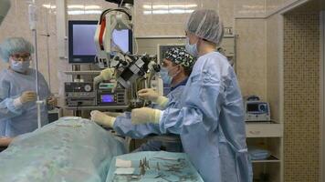 A group of surgeons, a man and two women in a large operating room perform microscopic surgery on ENT organs using a surgical microscope.Innovative technologies in medicine video